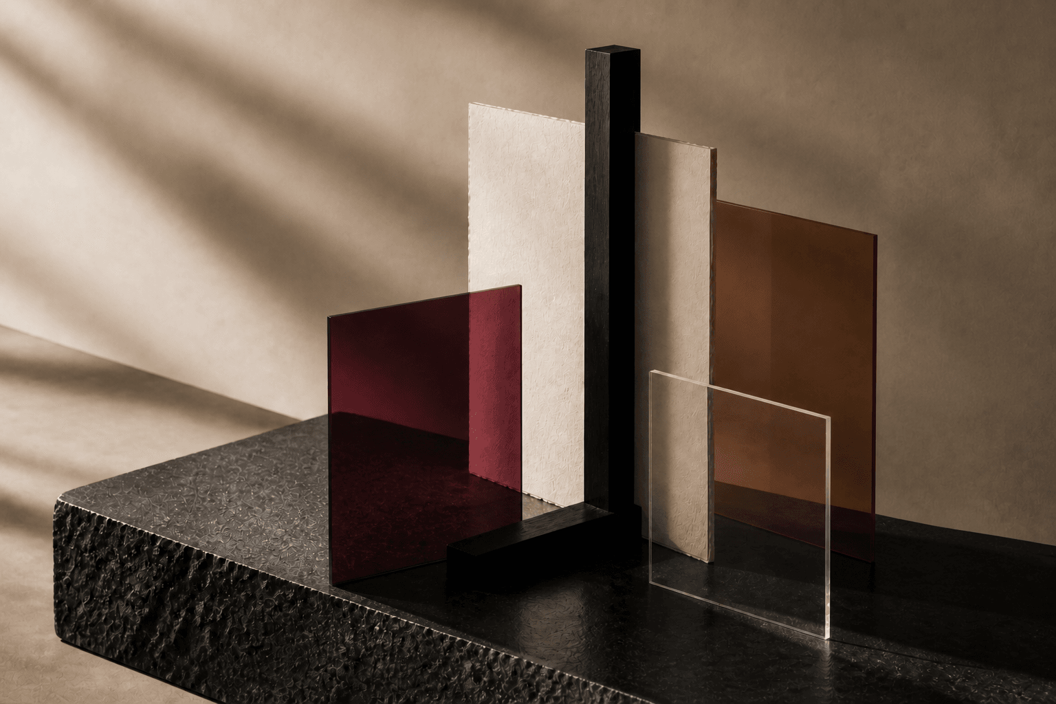 A warm editorial still life of layered papers, stone, glass, and architectural light
